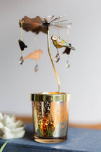 Decorative candle holder with birds and crystals on a table