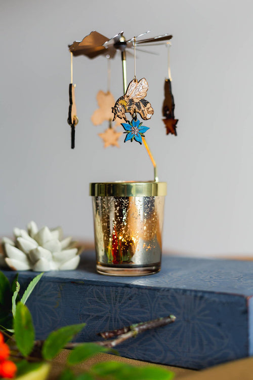 Decorative candle holder with hanging ornaments on a textured surface